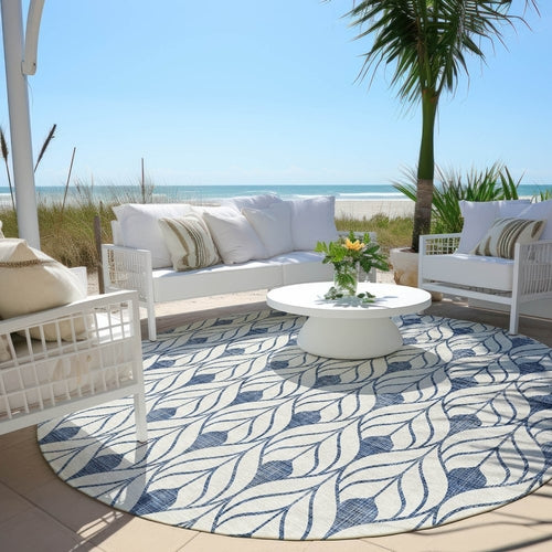 Blue and white round pattern rug in front of a set of couches outsideby the beach