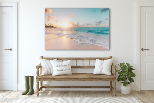 Beach wall art on a wall on top of a brown bench with white pillows a plant pot and boots