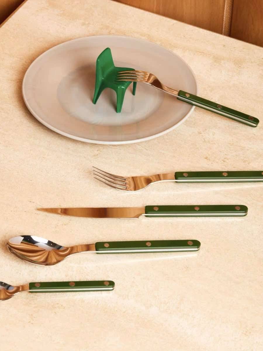 Green silver cutlery with plates on a table