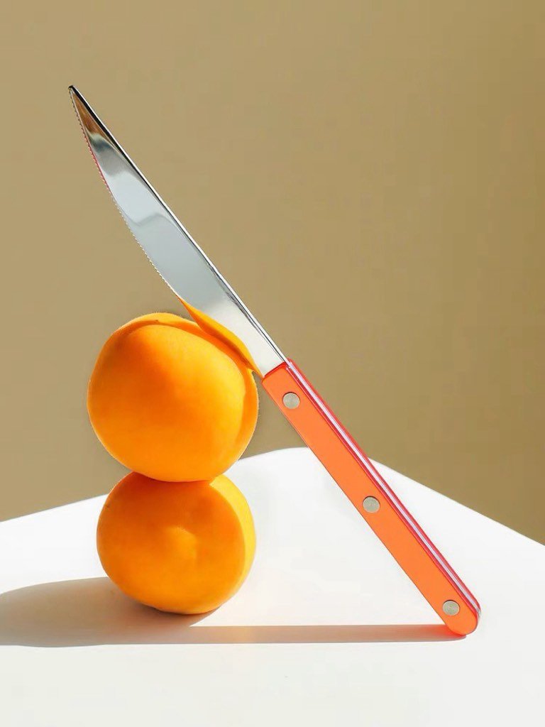 Orange silver knife with oranges on a table