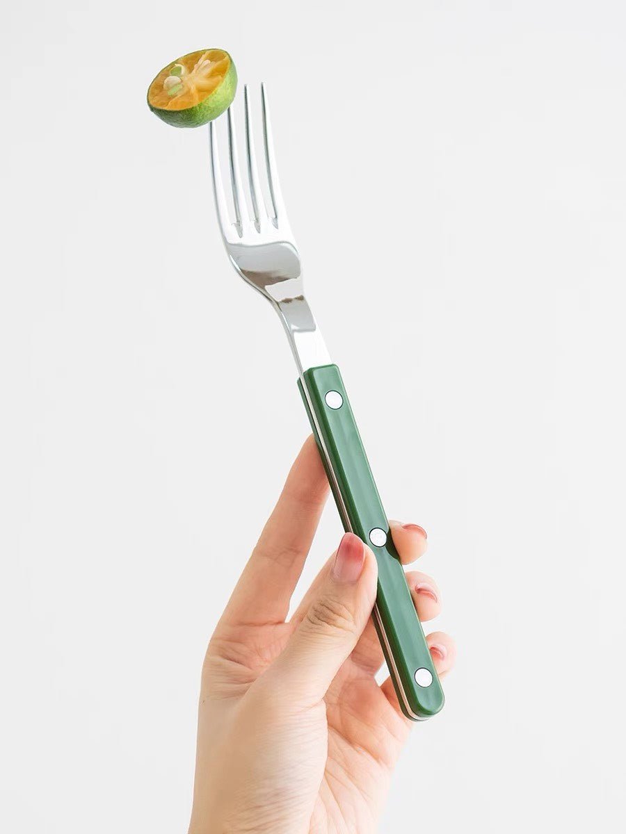 Green silver fork with lemon in a hand
