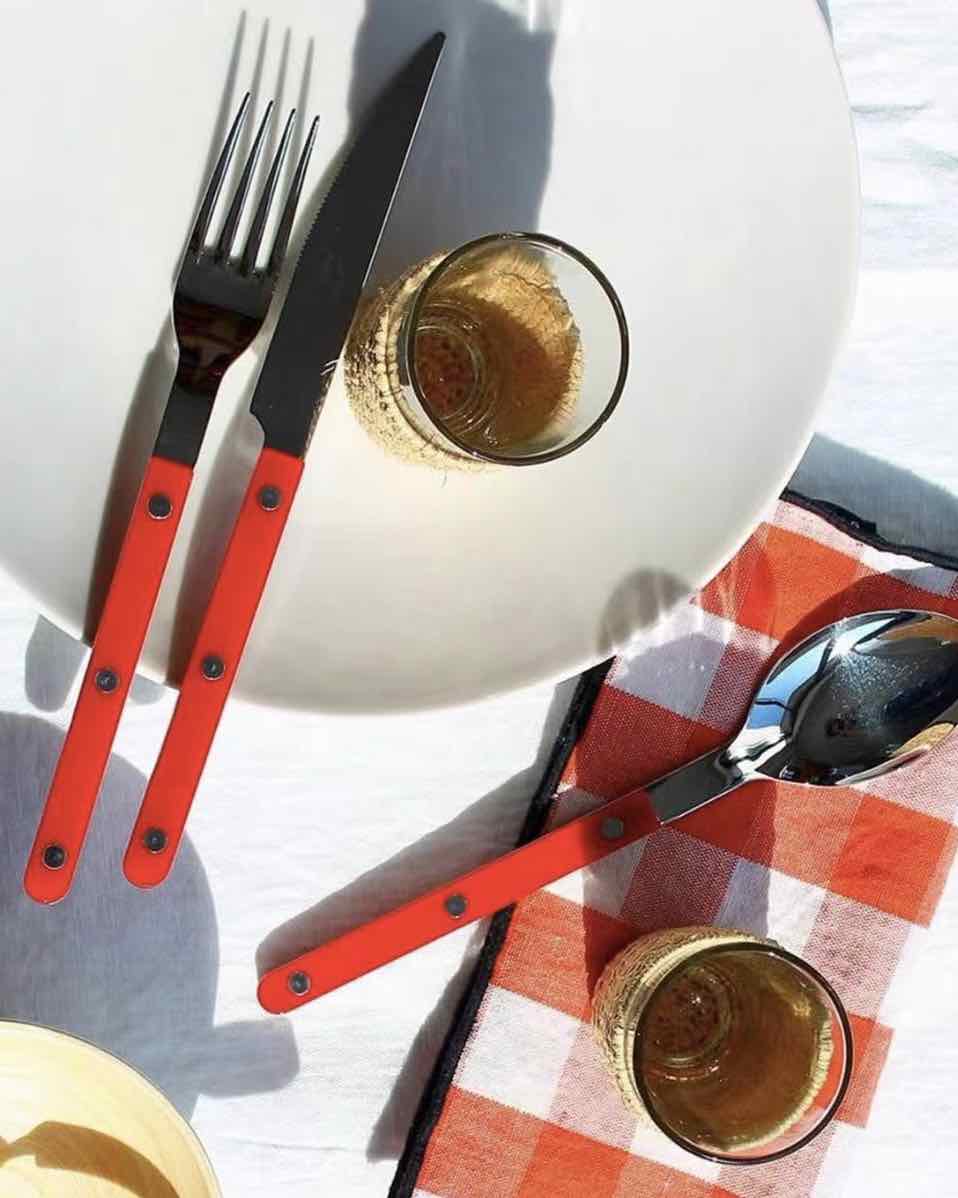 Orange silver cutlery on a table with plate