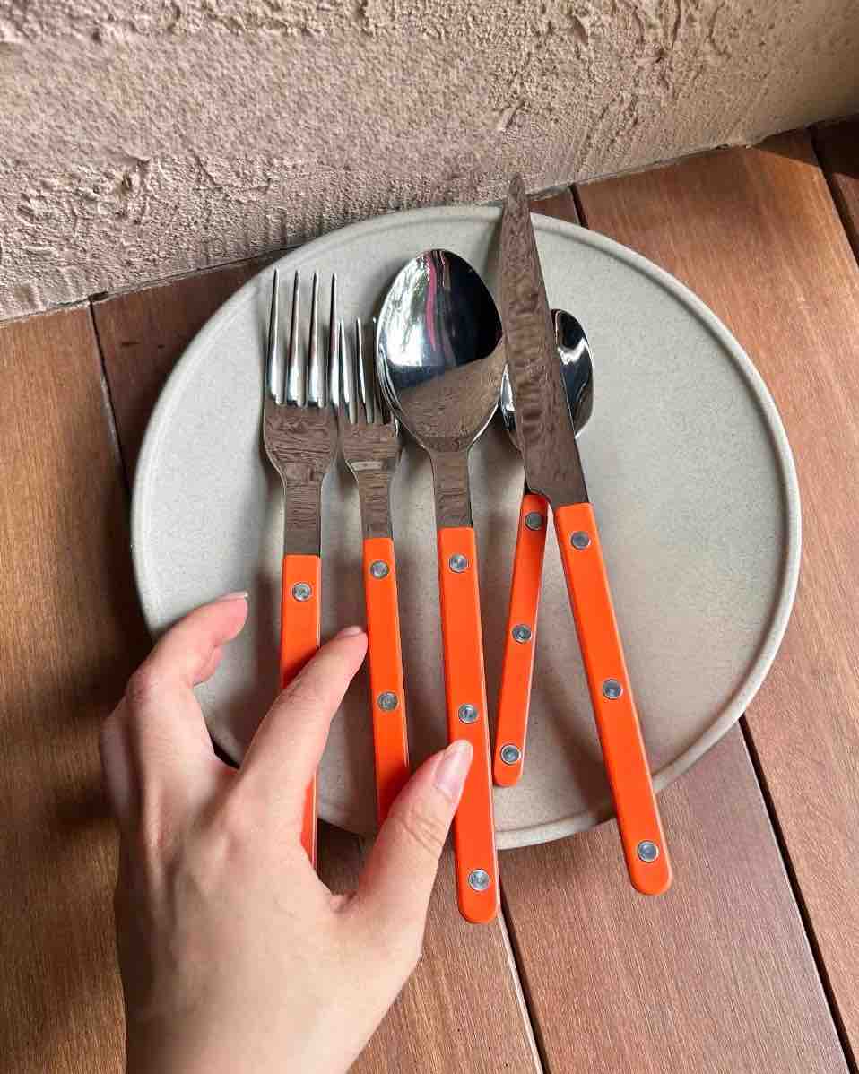 Orange silver cutlery with plates on a table