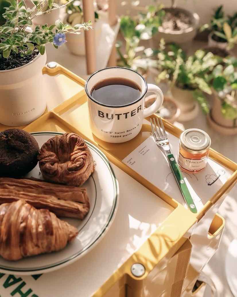 Green fork with coffee and muffins on a table with flowers